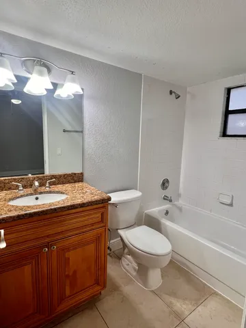 a bathroom with a granite countertop toilet a sink and a mirror