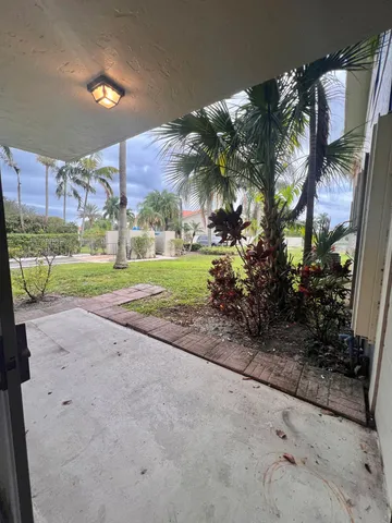 a view of a house with a yard and coconut trees