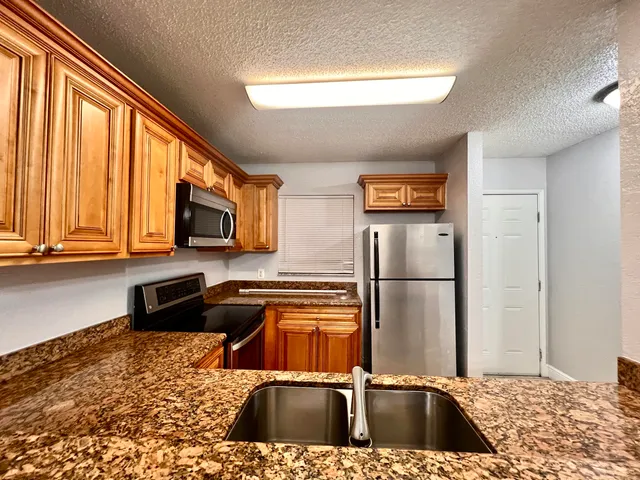 a kitchen with stainless steel appliances granite countertop a refrigerator a stove top oven a sink and dishwasher