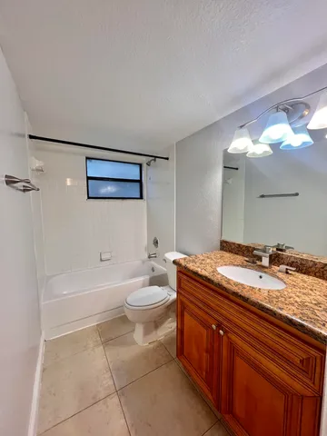 a spacious bathroom with a granite countertop sink mirror vanity and toilet