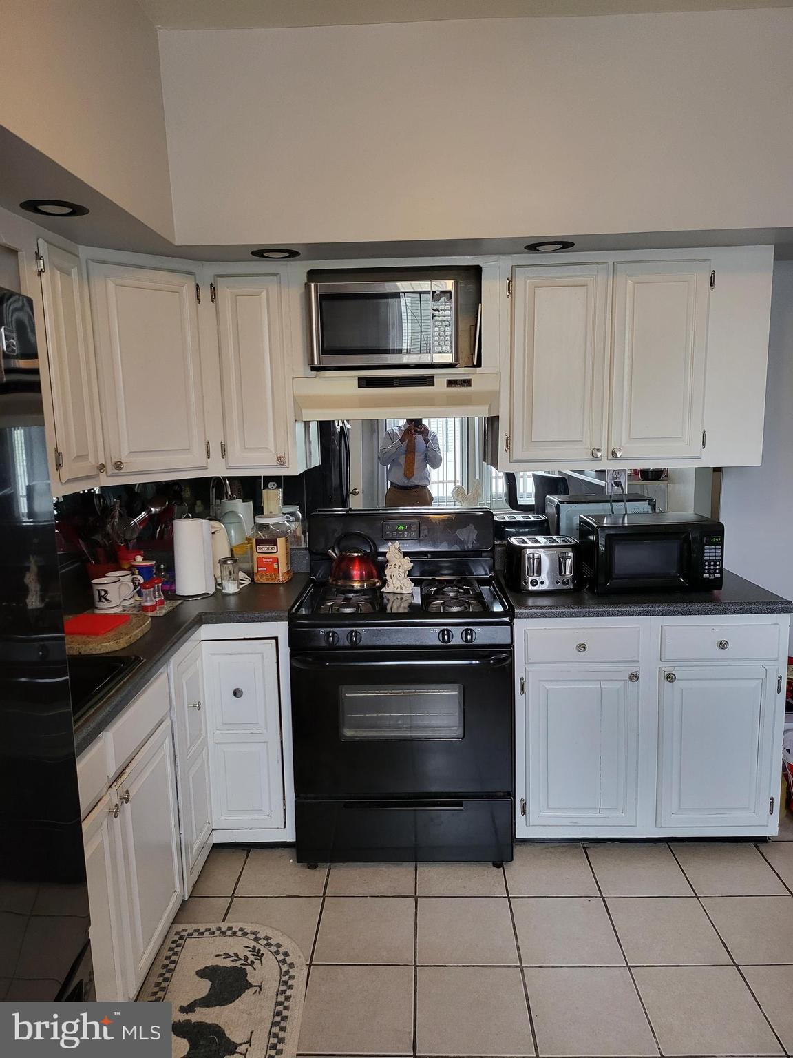 935 Howe Street Camden, NJ 08104 - Photo 5 of 14 a white kitchen with stainless steel appliances granite countertop a stove a sink and a microwave