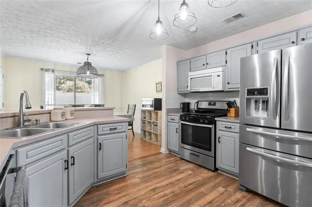 a kitchen with stainless steel appliances a sink cabinets and wooden floor