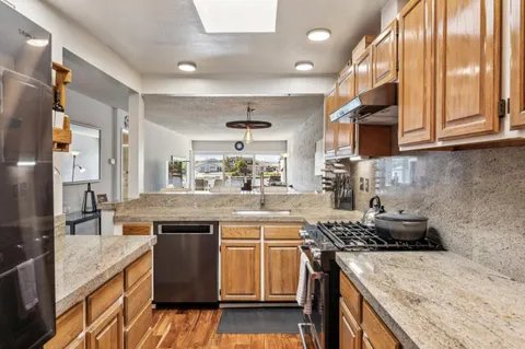 a kitchen with granite countertop kitchen island wooden cabinets and stainless steel appliances