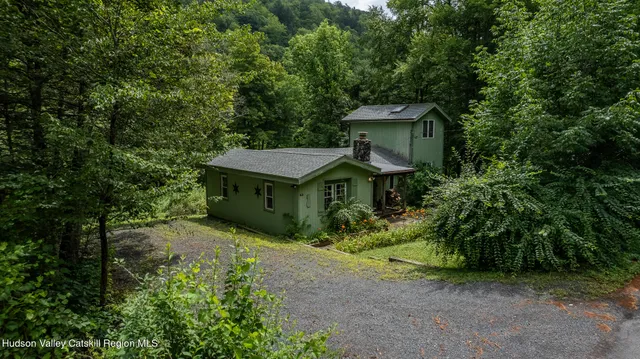 a view of a house with a yard and large trees