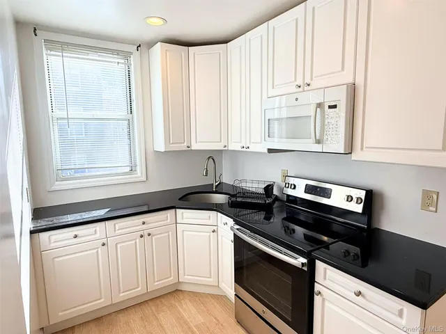 a kitchen with granite countertop white cabinets and appliances