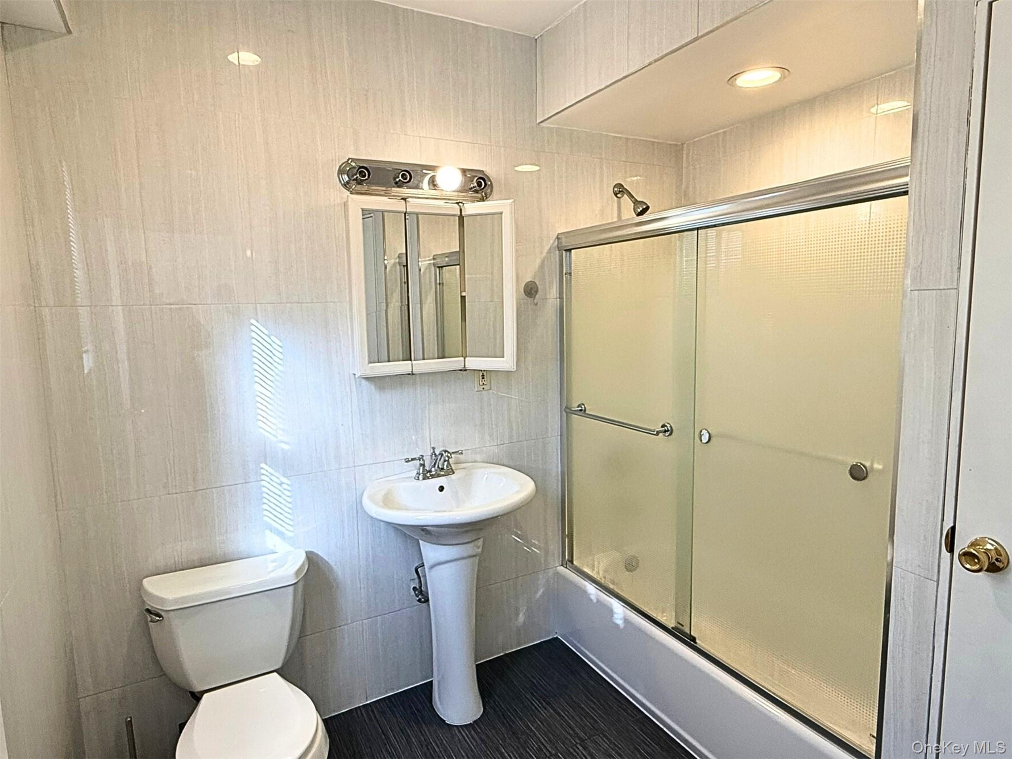 52-05 35th Street, Unit 2 Queens, NY 11101 - Photo 30 of 32 a bathroom with a sink mirror toilet and shower