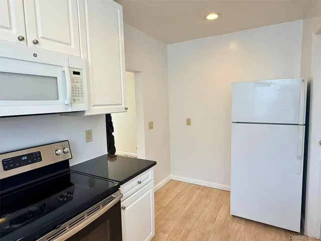 a kitchen with granite countertop a refrigerator a stove a microwave and cabinets