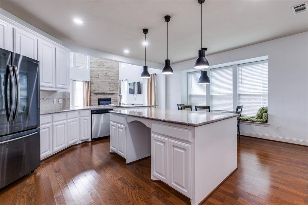 3620 Acropolis Way Plano, TX 75074 - Photo 9 of 25 a kitchen with granite countertop a white refrigerator a sink dishwasher a oven and a dining table with wooden floor