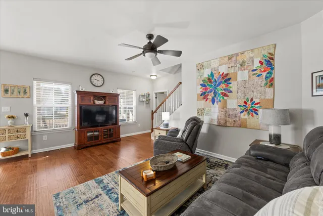 a kitchen with stainless steel appliances kitchen island granite countertop a stove a sink dishwasher a refrigerator white cabinets and wooden floor next to a window