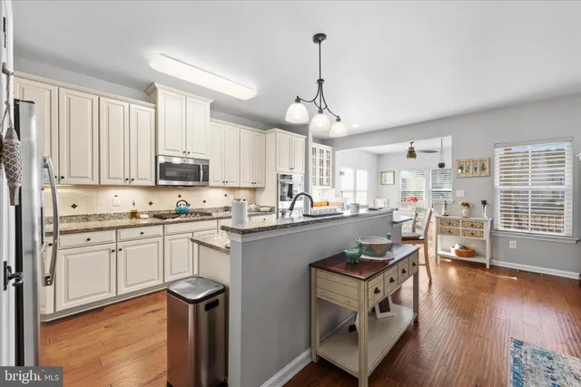 a kitchen with stainless steel appliances a stove a sink dishwasher a refrigerator white cabinets and wooden floor