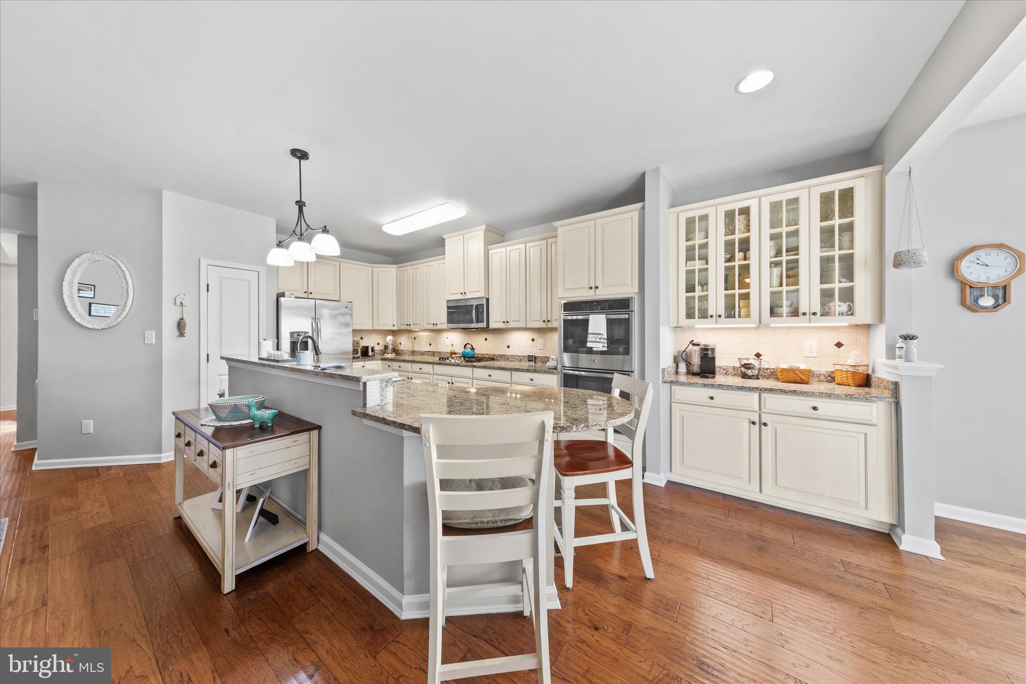 21329 North Acorn Way Lewes, DE 19958 - Photo 16 of 68 a kitchen with stainless steel appliances kitchen island granite countertop a stove a sink dishwasher a refrigerator white cabinets and wooden floor next to a window