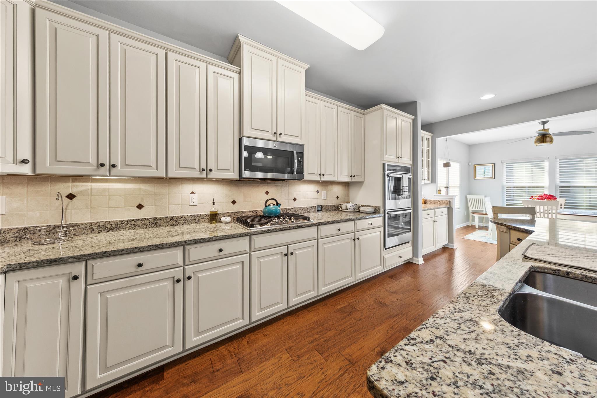 21329 North Acorn Way Lewes, DE 19958 - Photo 18 of 68 a kitchen with stainless steel appliances granite countertop a stove a sink and white cabinets with wooden floor