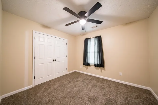 an empty room with window and ceiling fan