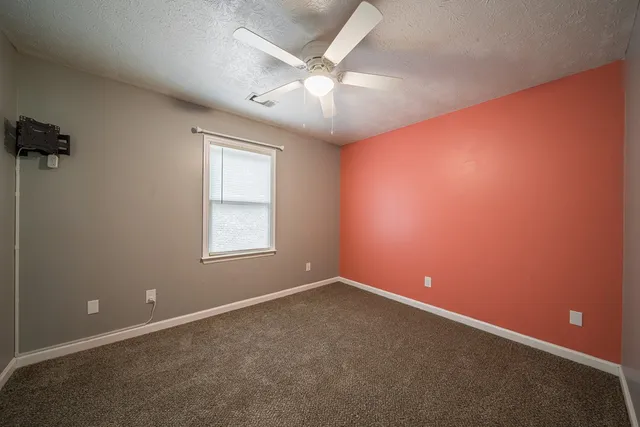 an empty room with a ceiling fan and window