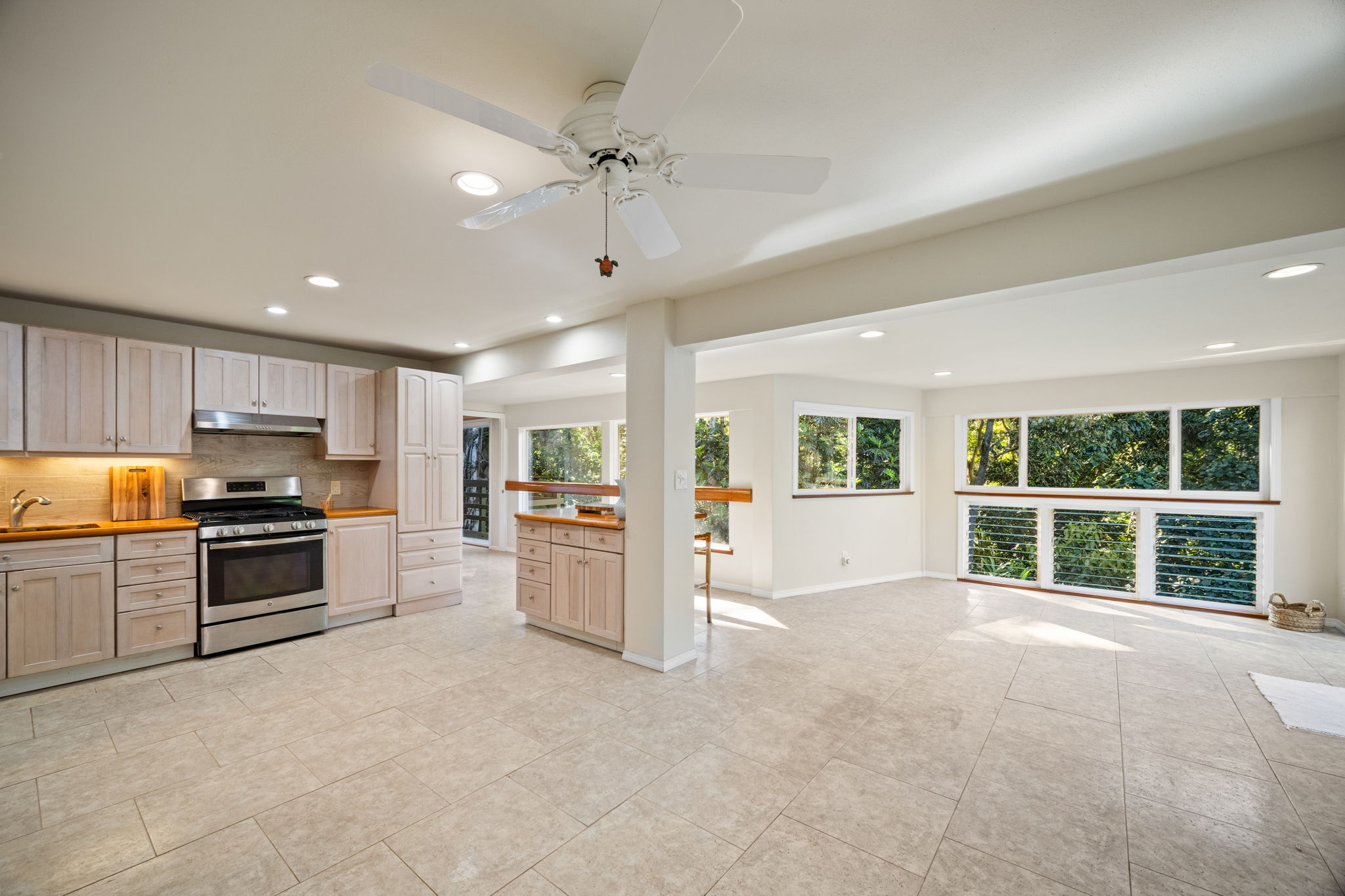 6050 C Kapahi Road Kapaa, HI 96746 - Photo 17 of 30 a large kitchen with stainless steel appliances kitchen island granite countertop a refrigerator a stove a sink a dining table and chairs with wooden floor