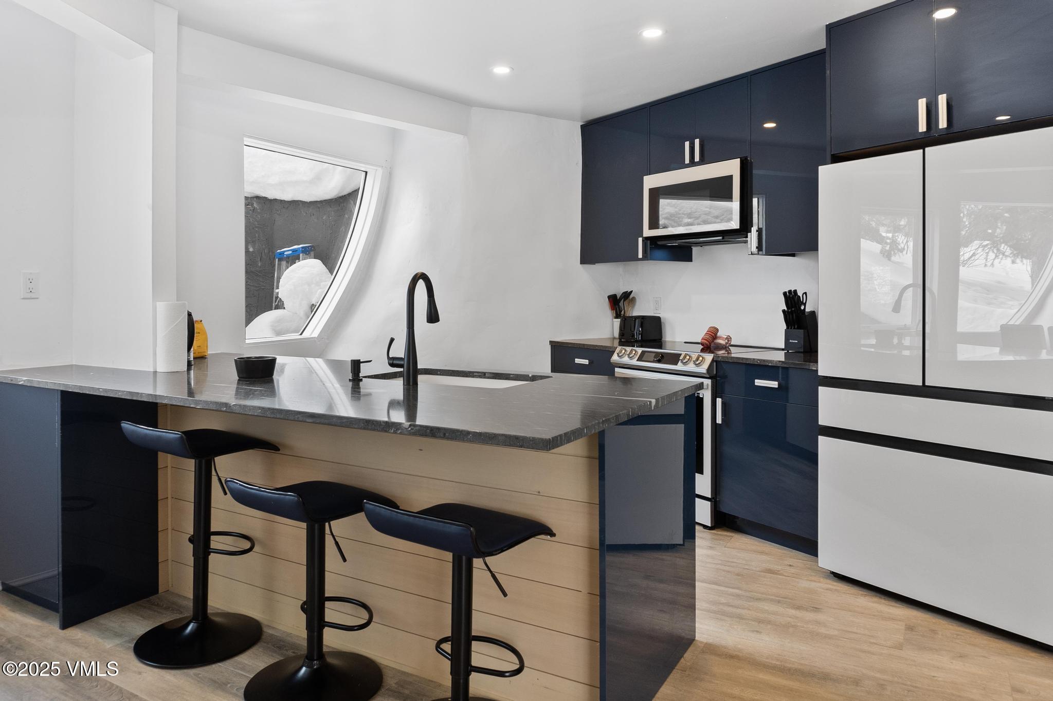 2940 Basingdale Boulevard, Unit 2 Vail, CO 81657 - Photo 4 of 28 a kitchen with a table chairs refrigerator and microwave