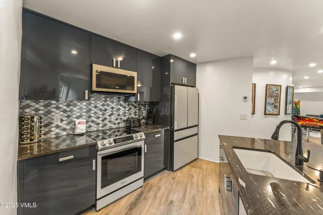 a view of a kitchen with wooden floor and an empty refrigerator