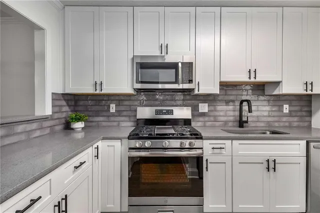 a kitchen with stainless steel appliances granite countertop a stove a white cabinets and a granite counter tops