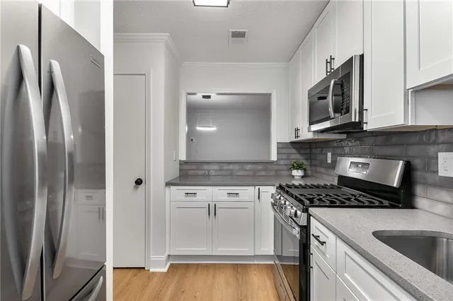 a kitchen with stainless steel appliances granite countertop a refrigerator a stove and a sink with wooden floor