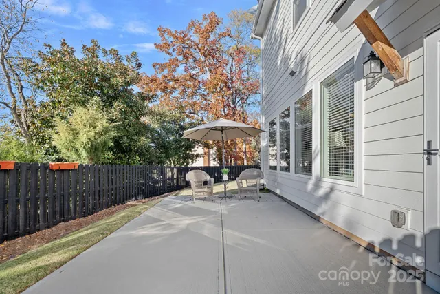 a view of a patio with a table and chairs under an umbrella with wooden fence