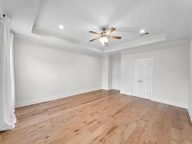 a view of empty room with wooden floor and fan