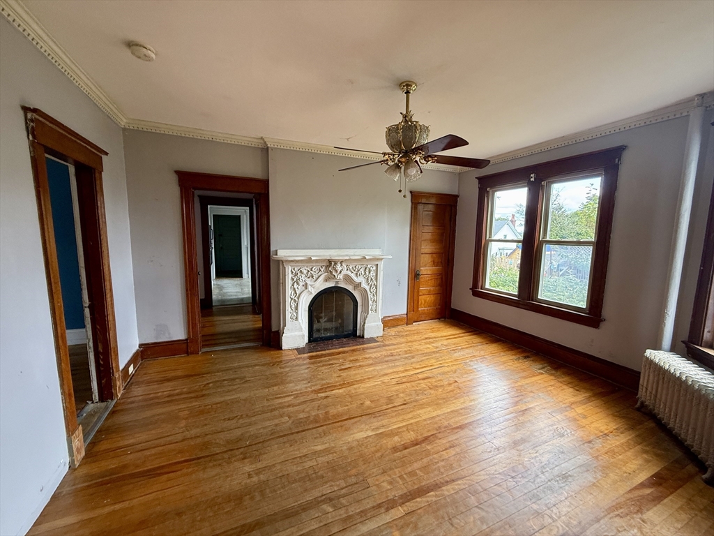 22 Baker Street Worcester, MA 01603 - Photo 6 of 35 a view of empty room with fireplace wooden floor and fan