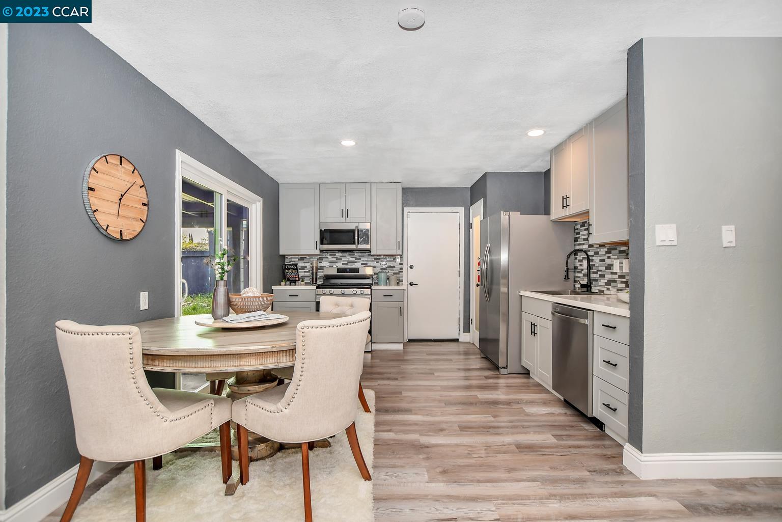 a kitchen with stainless steel appliances kitchen island granite countertop a refrigerator a stove a sink and a dining table with wooden floor