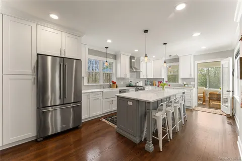a kitchen with stainless steel appliances granite countertop a refrigerator a stove a sink a dining table and chairs with wooden floor