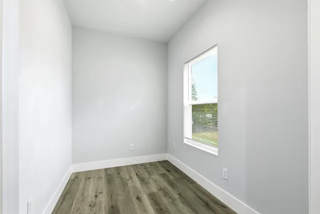 a view of an empty room with wooden floor and a window