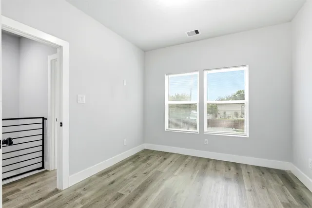 an empty room with wooden floor and windows