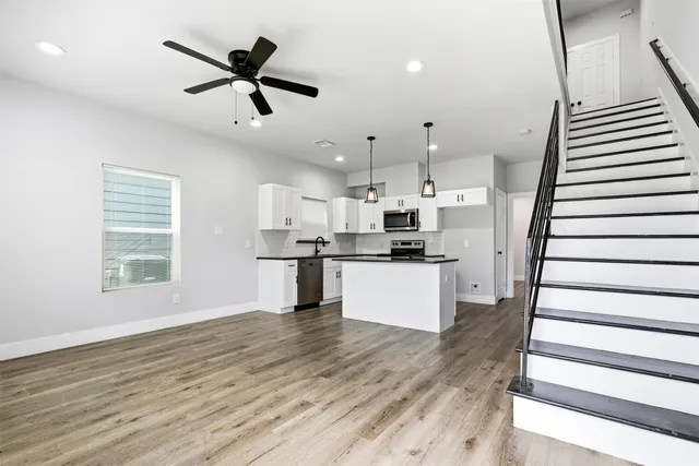 a kitchen with stainless steel appliances kitchen island hardwood floor and a window