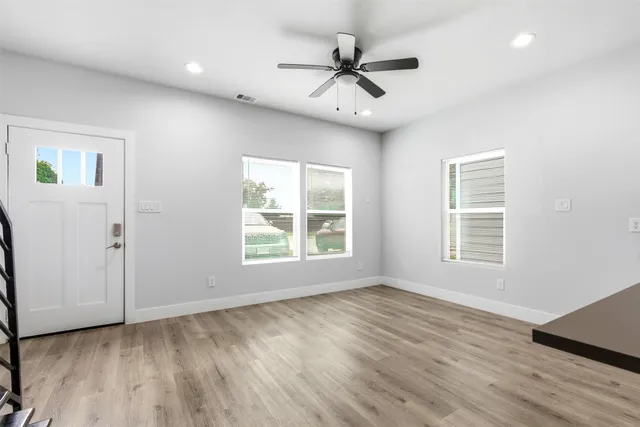 a view of an empty room with a window and wooden floor