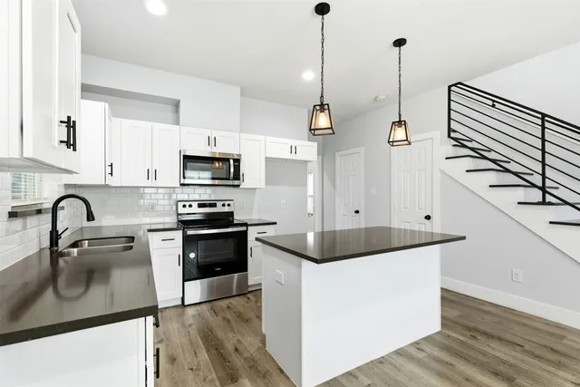 a kitchen with stainless steel appliances granite countertop a sink a stove and a wooden floor