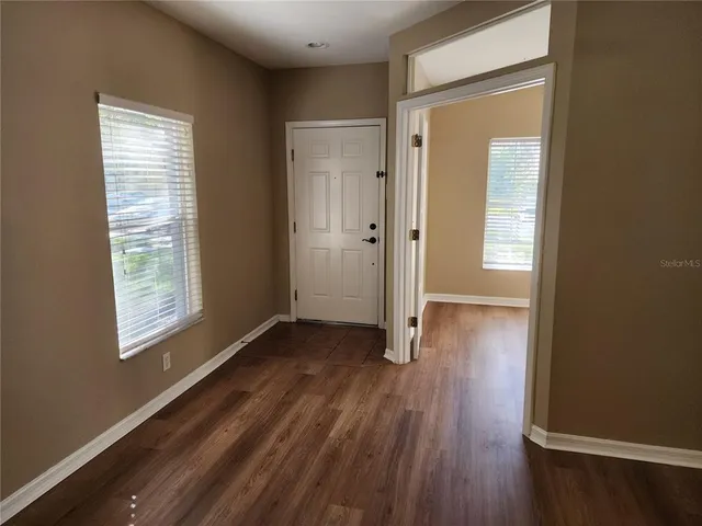 an empty room with wooden floor and entrance