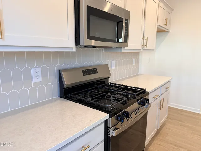 a kitchen with granite countertop a stove and a microwave