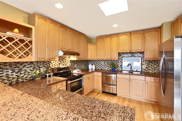 a kitchen with stainless steel appliances granite countertop a stove a sink and a microwave