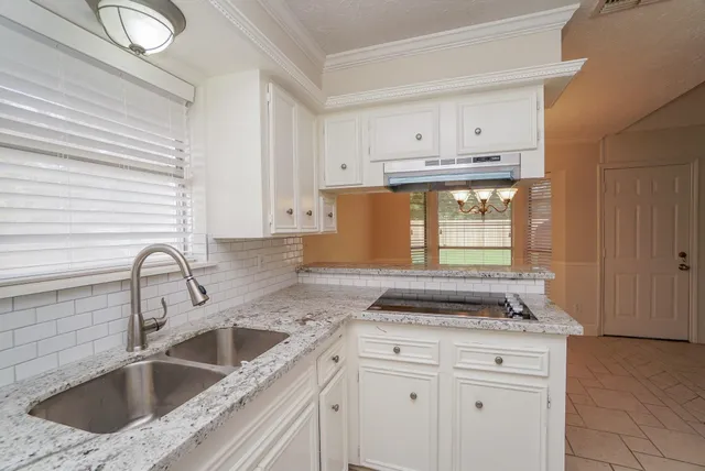 a kitchen with granite countertop a sink stove and cabinets