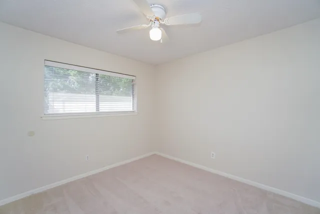 an empty room with a window and a fan