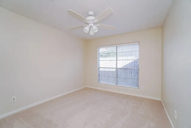 an empty room with chandelier fan and windows