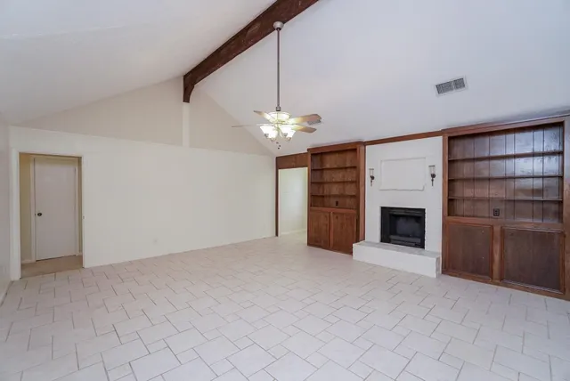 a view of a livingroom with a fireplace a ceiling fan and window