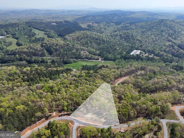 an aerial view of a house with a yard and mountain view in back
