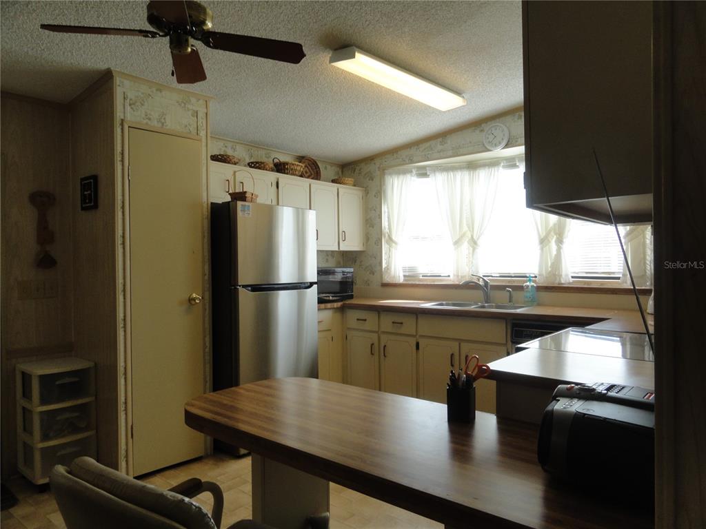 6233 Parakeet Road Englewood, FL 34224 - Photo 9 of 27 a kitchen with stainless steel appliances granite countertop a refrigerator a sink dishwasher a stove and white countertops with wooden floor