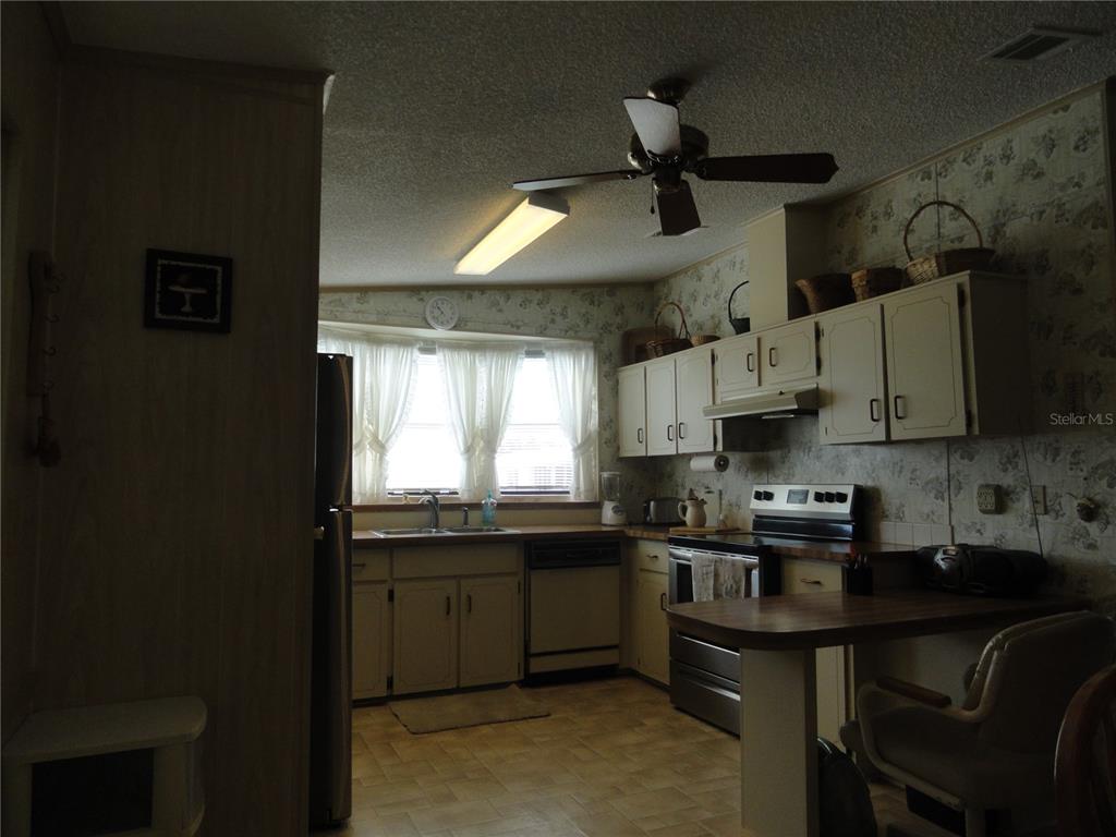 6233 Parakeet Road Englewood, FL 34224 - Photo 10 of 27 a kitchen with stainless steel appliances granite countertop a sink a stove a chimney a refrigerator and cabinets