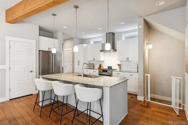 a kitchen with stainless steel appliances granite countertop a sink a stove a refrigerator and island with wooden floor
