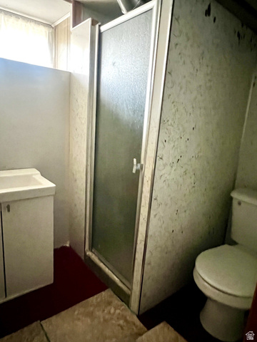 1766 Kenilworth Road Spring Glen, UT 84526 - Photo 23 of 24 Compact bathroom featuring a stand-up shower with a clear panel door, a white toilet, and a vanity with an integrated sink