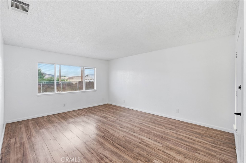 21739 Panoche Road Apple Valley, CA 92308 - Photo 7 of 49 a view of an empty room with wooden floor and a window