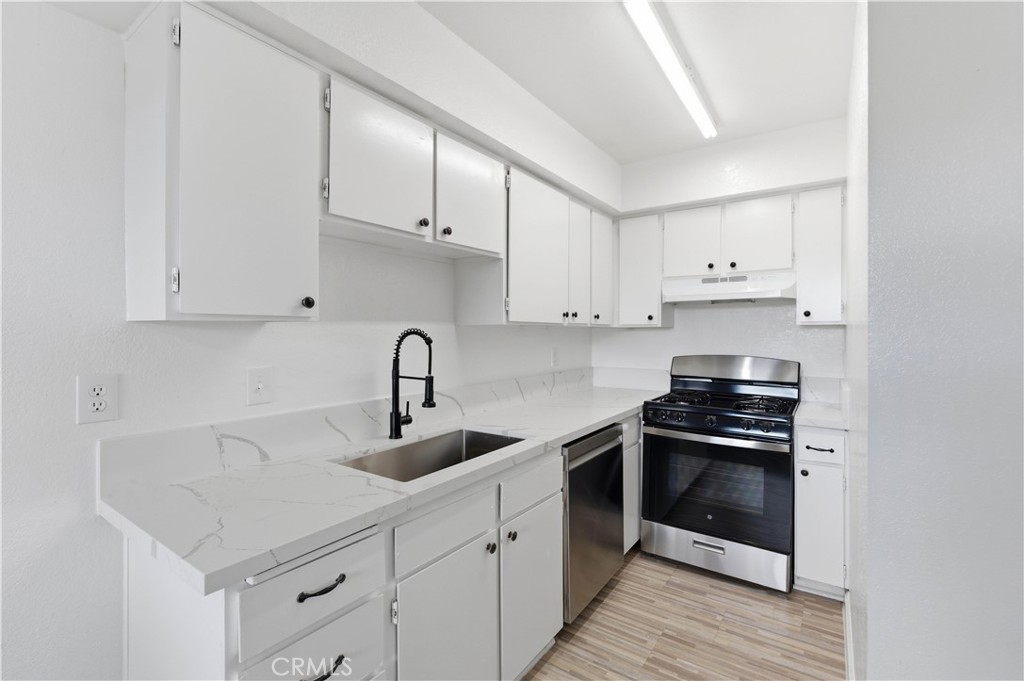 21739 Panoche Road Apple Valley, CA 92308 - Photo 10 of 49 a kitchen with white cabinets and appliances