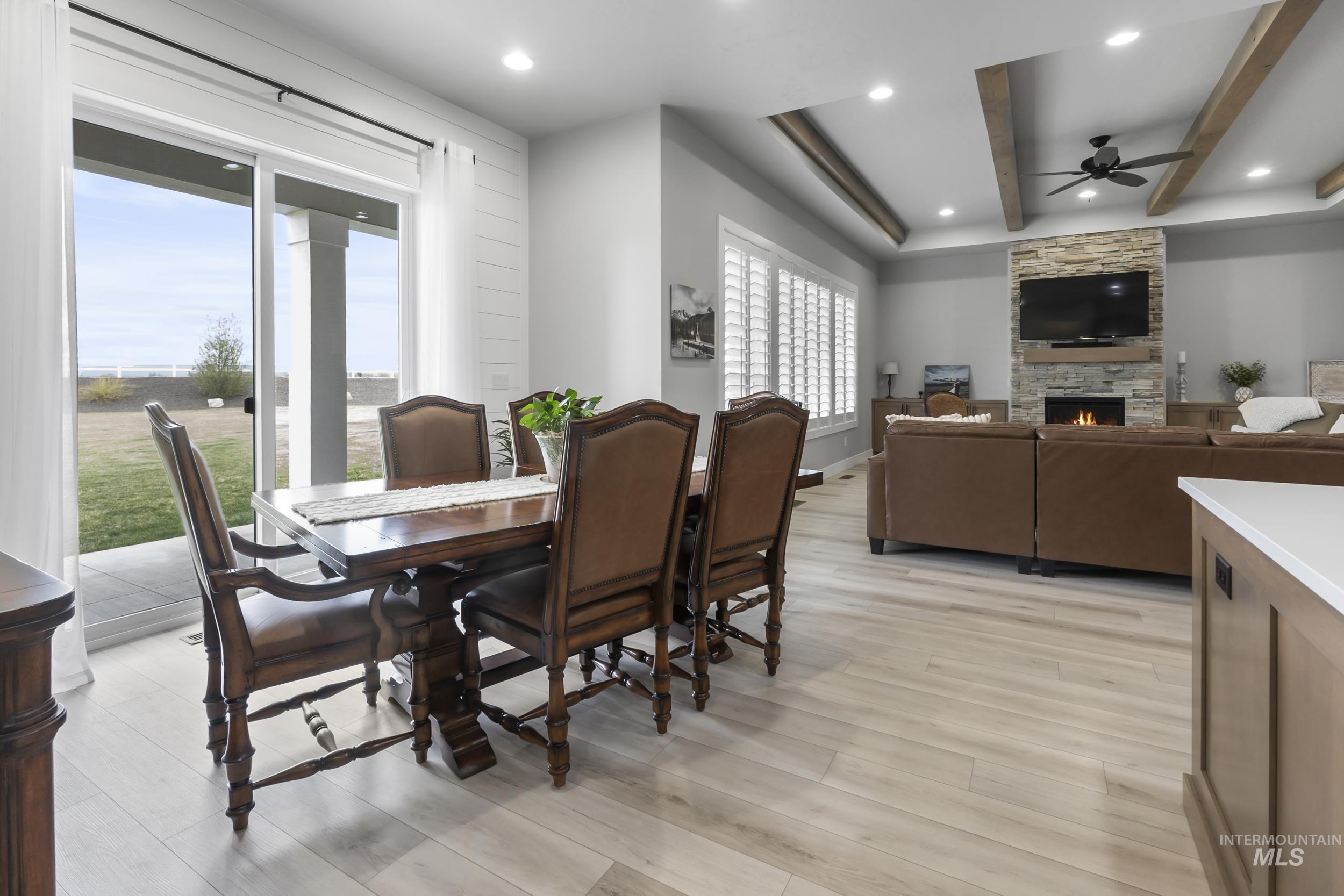 24696 Regal Road Middleton, ID 83644 - Photo 5 of 24 Dining room with light wood-type flooring, ceiling fan, beamed ceiling, recessed lighting, and a stone fireplace