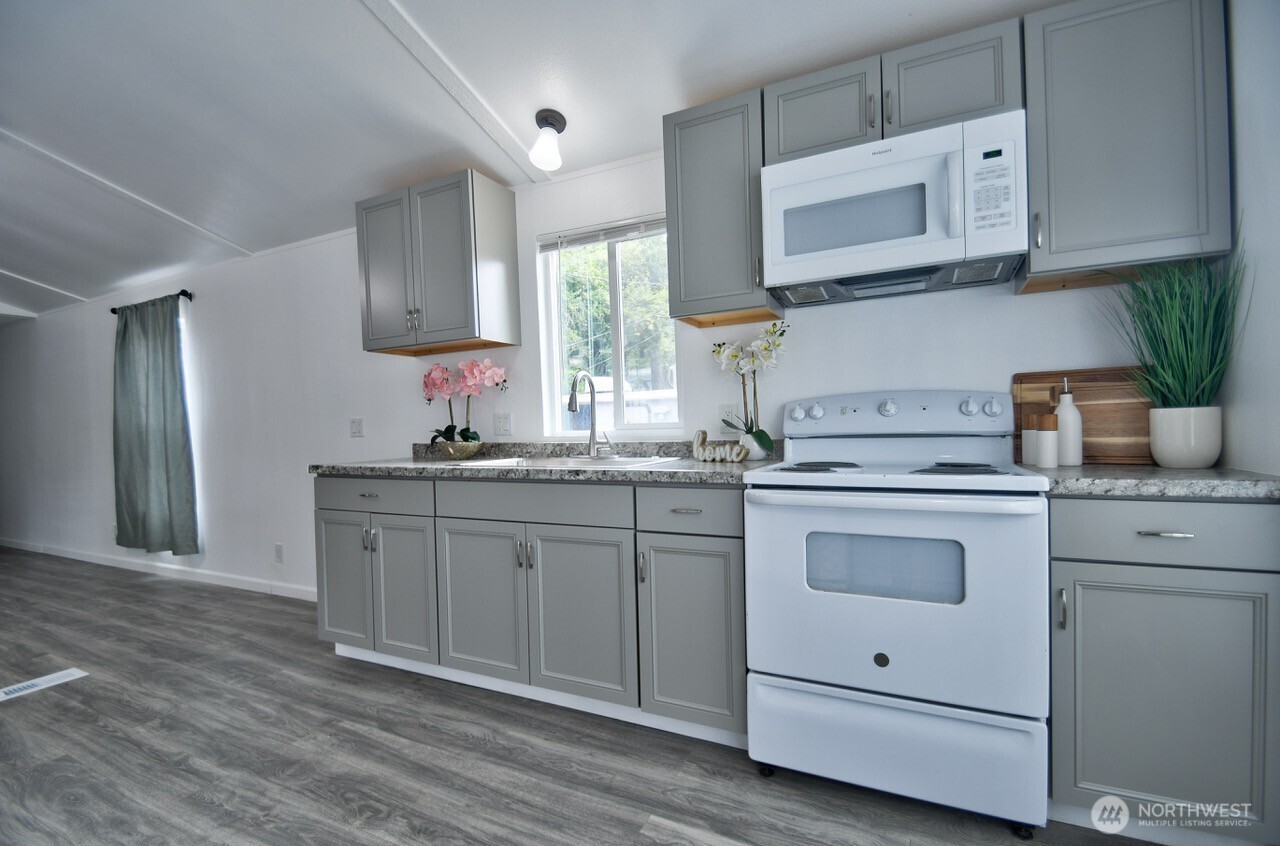 2115 Rocky Point Road Northwest, Unit 22 Bremerton, WA 98312 - Photo 8 of 16 a kitchen with granite countertop white cabinets stainless steel appliances a sink and wooden floor