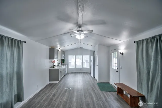 a view of a hallway with wooden floor and a kitchen